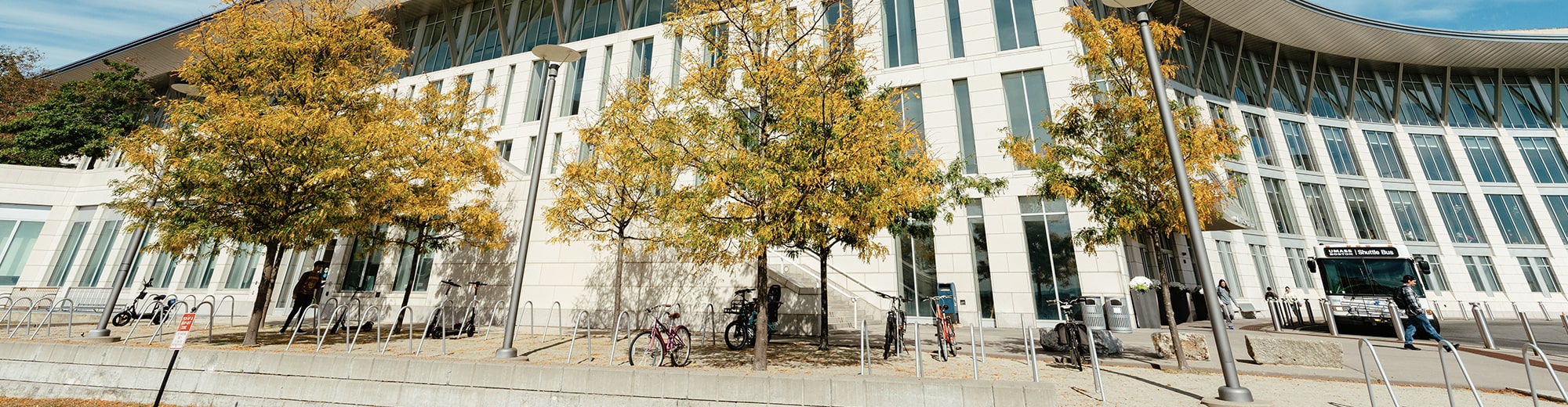 Students walk up steps to plaza through fall trees past Campus Center.