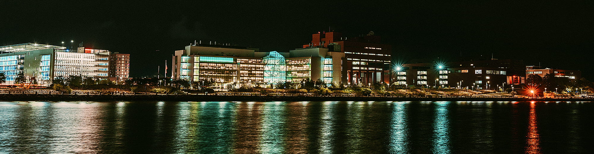 Integrated Sciences Complex at night view from the water.