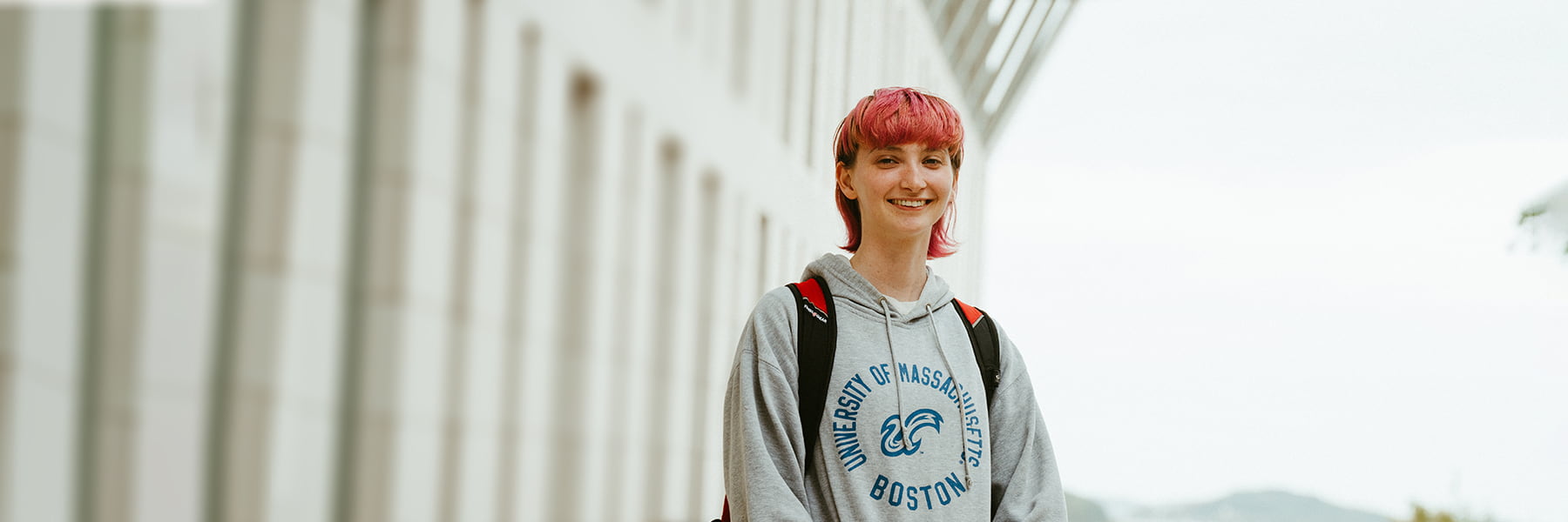 Student with pink hair walks by campus center.