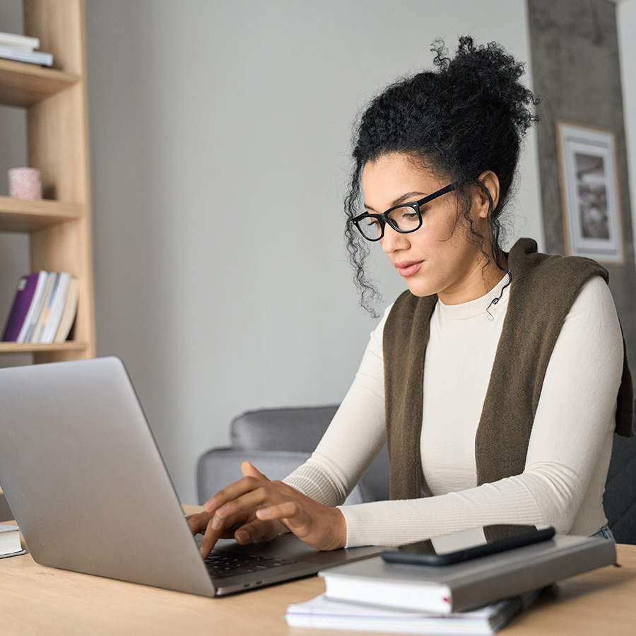 Female using a laptop with books on the table